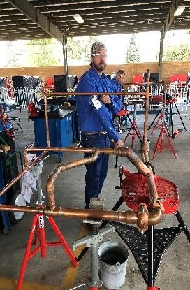 A welder standing behind welded copper joints