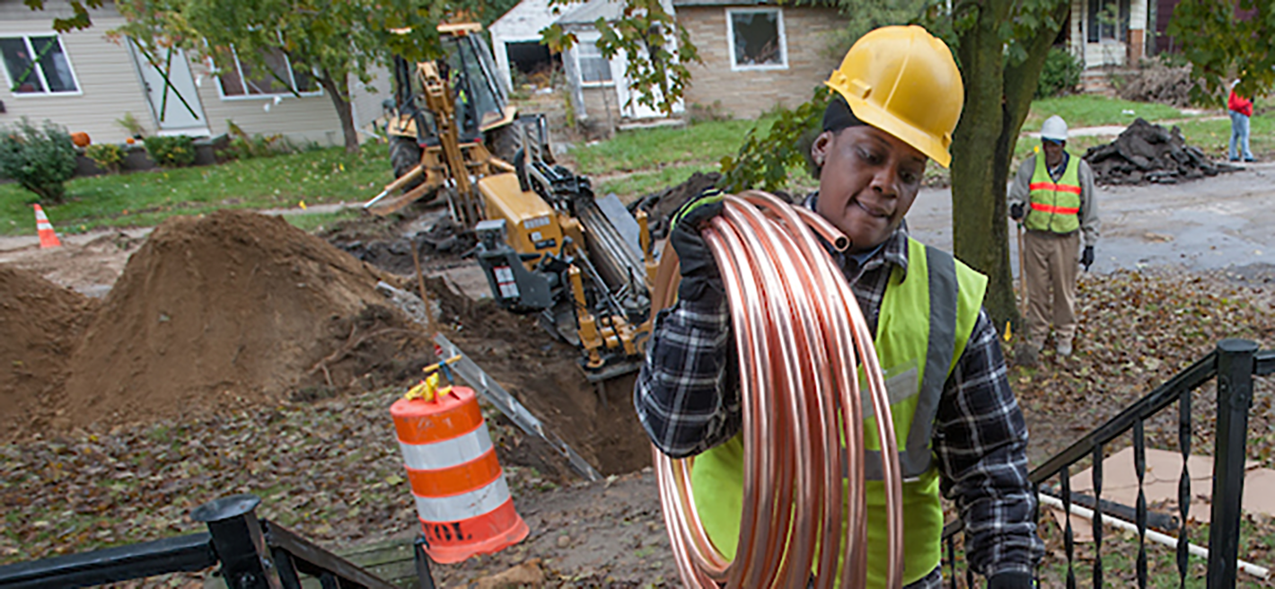 worker carrying copper piping