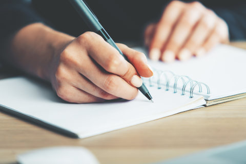 hands writing a letter with a pen